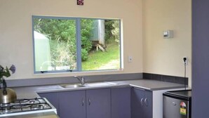 Cocina compacta con ventana, pileta, cocina y refrigerador.