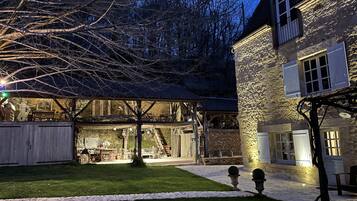 Un bâtiment en pierre doté d’un patio couvert, d’un arbre et d’une pelouse bien entretenue.