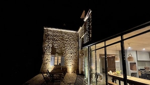 Terraza exterior con mobiliario de madera y un muro de piedra.