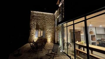 Une terrasse extérieure avec des meubles en bois et un mur en pierre.