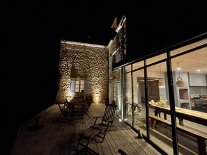 Une terrasse extérieure avec des meubles en bois et un mur en pierre.