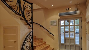 A staircase with a black metal railing, a wooden door, and a window with a view of the outside. - Hotel Garden (Novi Sad)