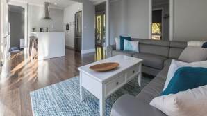 A modern living room with a grey sofa, a white coffee table, and a patterned rug.