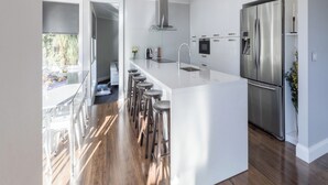 A modern kitchen with a large island, stainless steel appliances, and a view to the outdoor area.