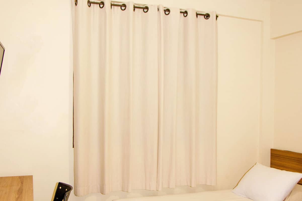 Een hotelkamer met twee bedden, een plafondventilator, een stoel en een bureau.
