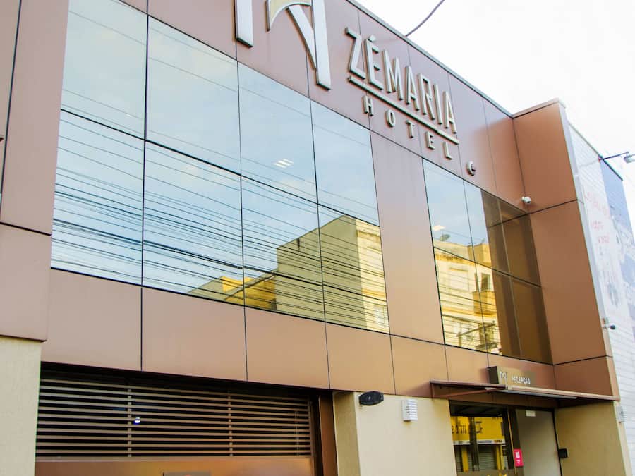 A modern hotel facade with a large glass entrance and a prominent sign reading "ZEMANIA HOTEL".