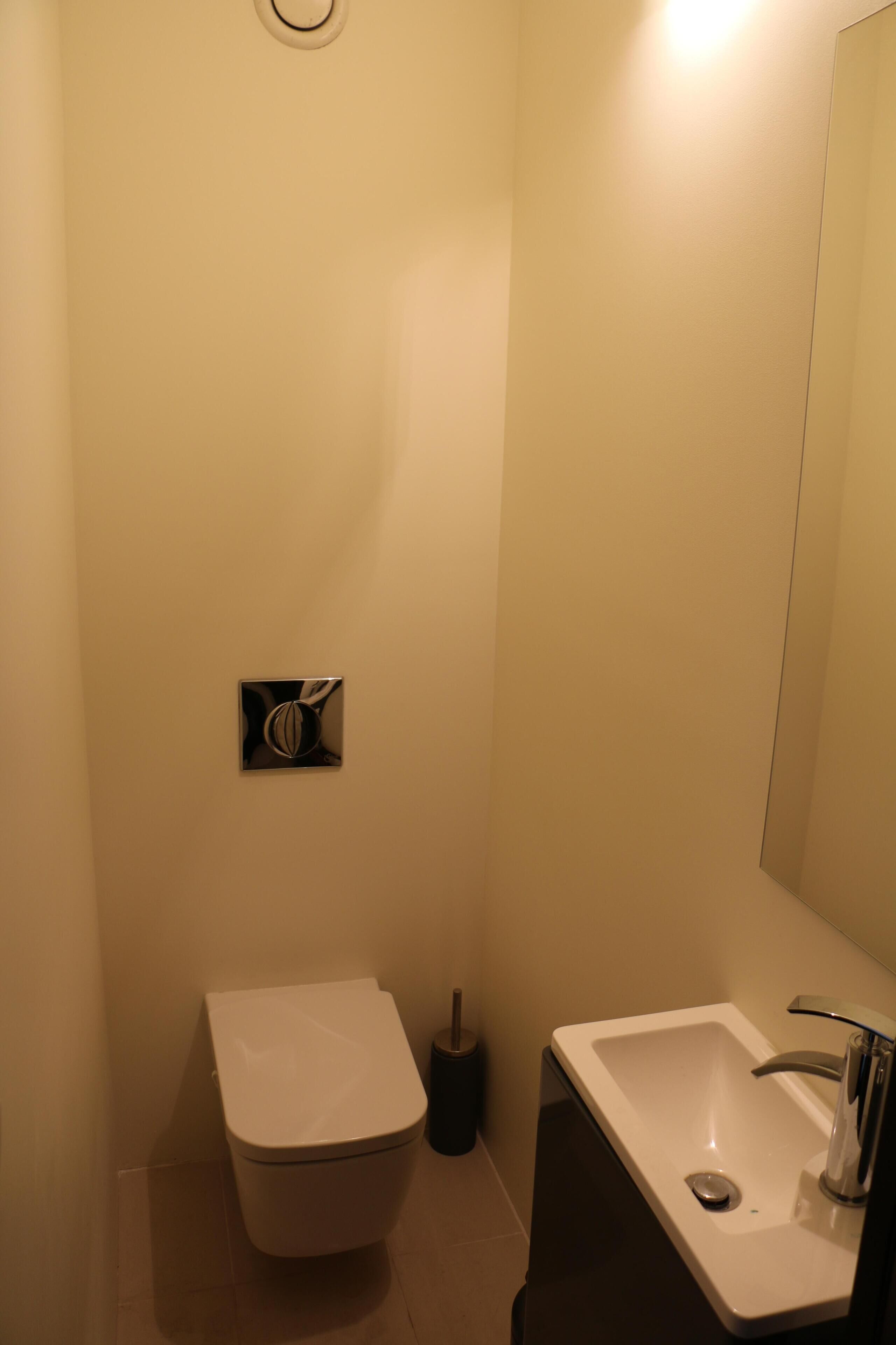 Une petite salle de bain moderne, équipée de toilettes, d’un lavabo et d’un miroir.