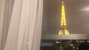 Uitzicht op de Eiffeltoren 's nachts door een raam met gordijnen.