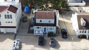 A two-story house with a front porch, a garage, and a driveway with three cars parked.