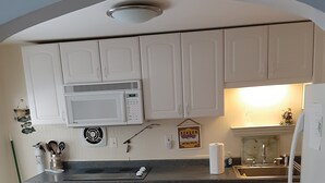 A kitchen with white cabinets, a microwave, a sink, and a refrigerator.