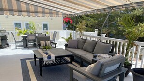 A covered outdoor seating area with a sofa, chairs, and a coffee table.
