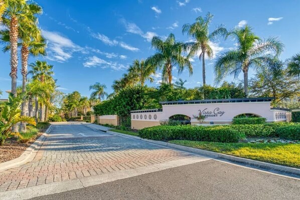 A paved pathway leading to Vista Cay Resort, surrounded by palm trees and greenery.