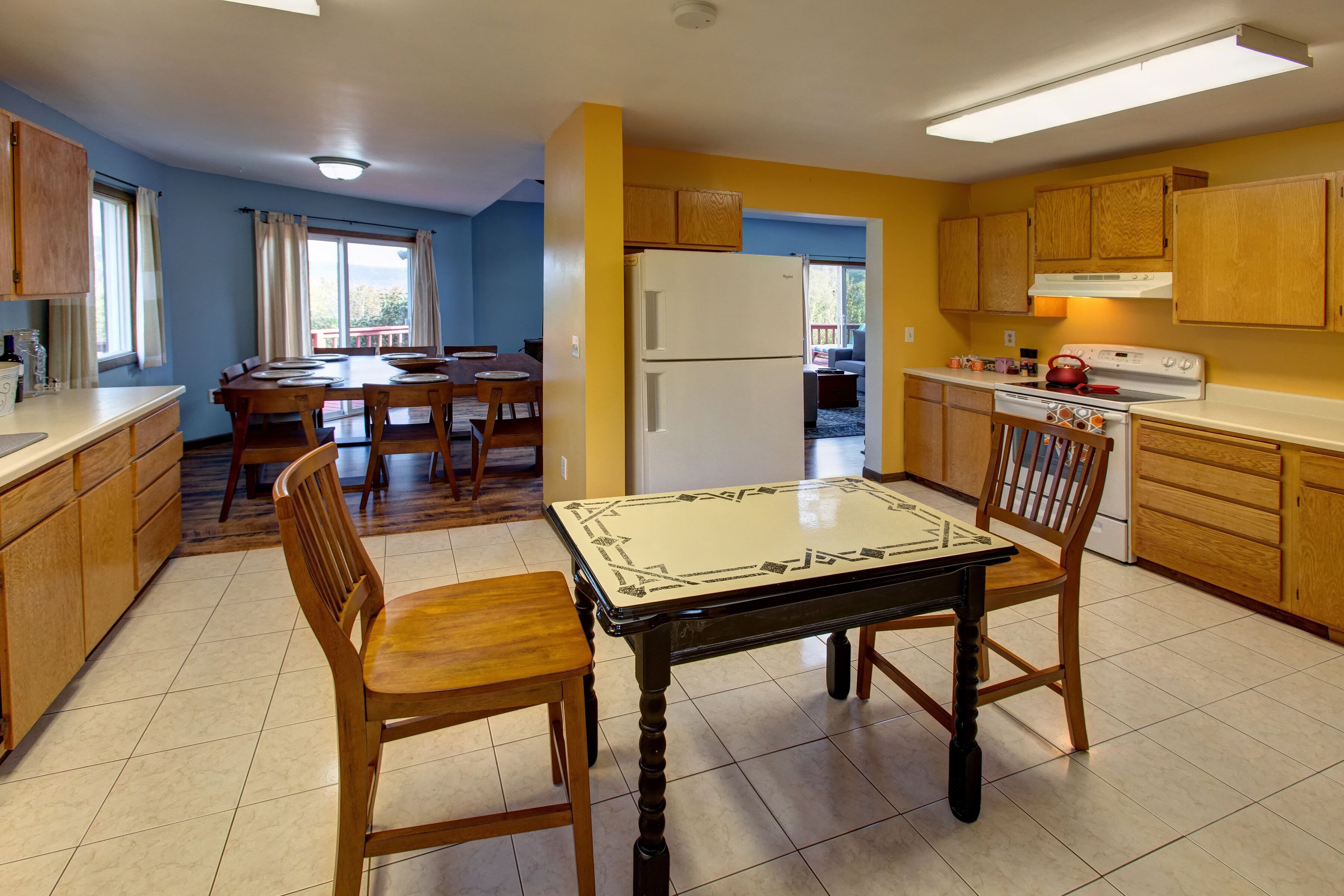 Una cocina con armarios de madera, un refrigerador, una estufa y un comedor con mesa y sillas.