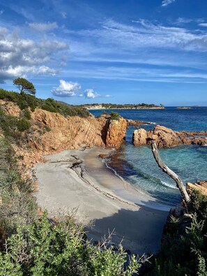 Un paisaje costero con acantilados rocosos, mar azul cristalino y una playa de arena.