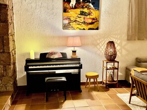 A piano with a fan, a candle, and a lamp on a wall.