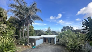 Ein Wohnhaus mit Garage, einer kleinen Gartenhütte und Auffahrt, umgeben von üppigem Grün und Bäumen.