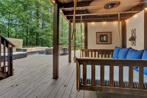Eine Holzterrasse mit Schaukel, Sitzgelegenheit und Lichterkette.