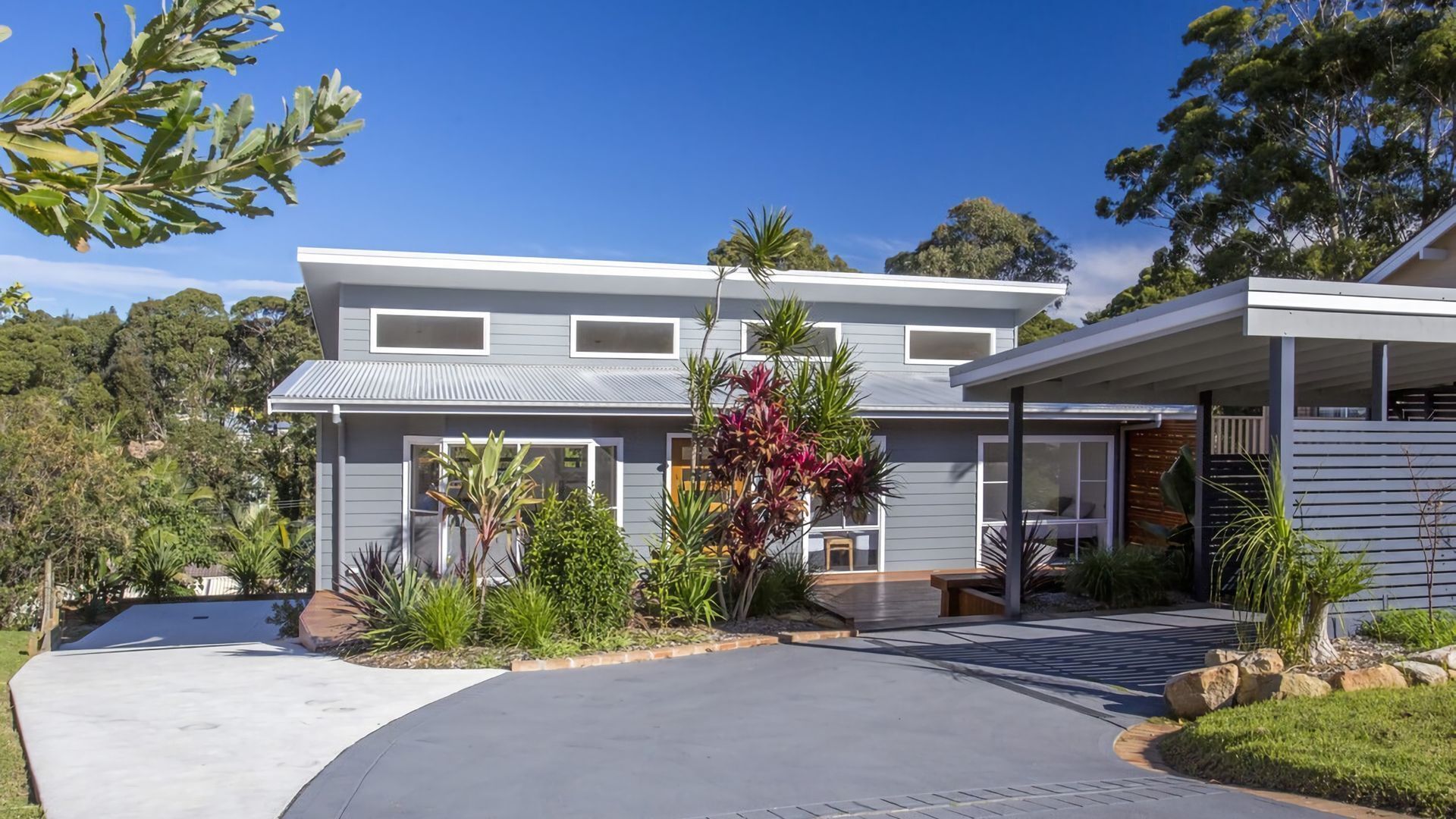 A modern two-story house with a covered patio and a driveway.