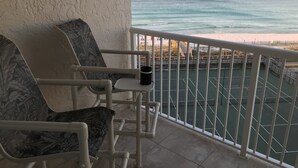 Un balcón con dos sillas y una mesa, con vista a la playa y el océano.