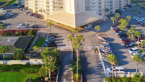 Un hotel de varios pisos con techo plano, estacionamiento y vista al océano.