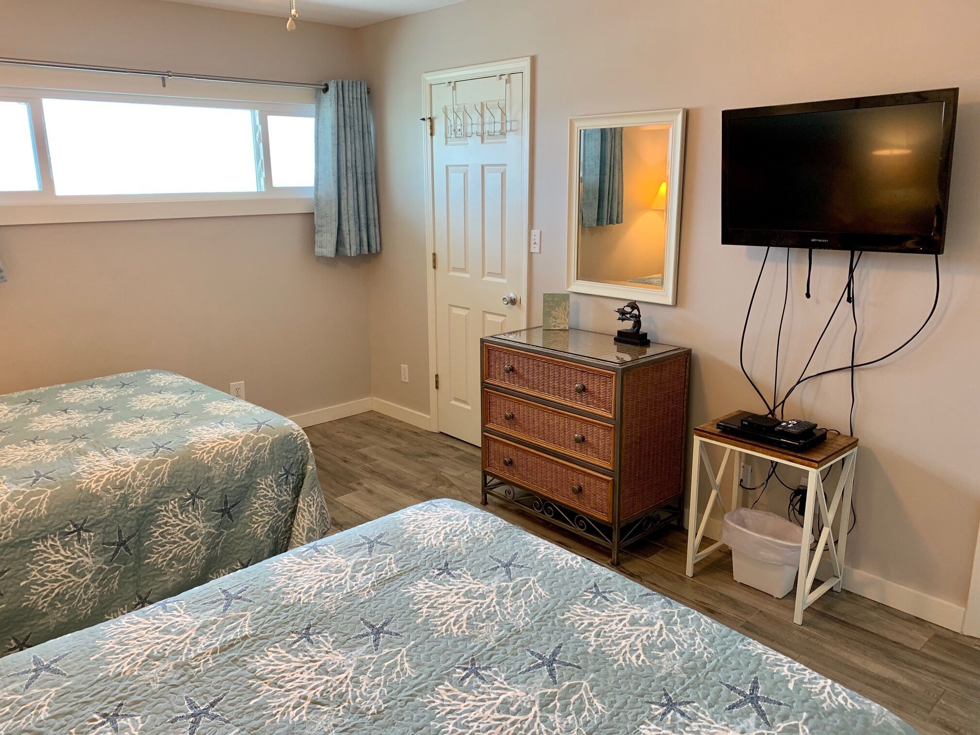 A bedroom with two beds, a dresser, a television, and a small table.