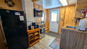 A compact kitchen with a black refrigerator, a microwave, a coffee maker, and a wooden cabinet. - Yellowstone's Treasure Cabin #1, few min drive to Yellowstone Park (Gardiner)