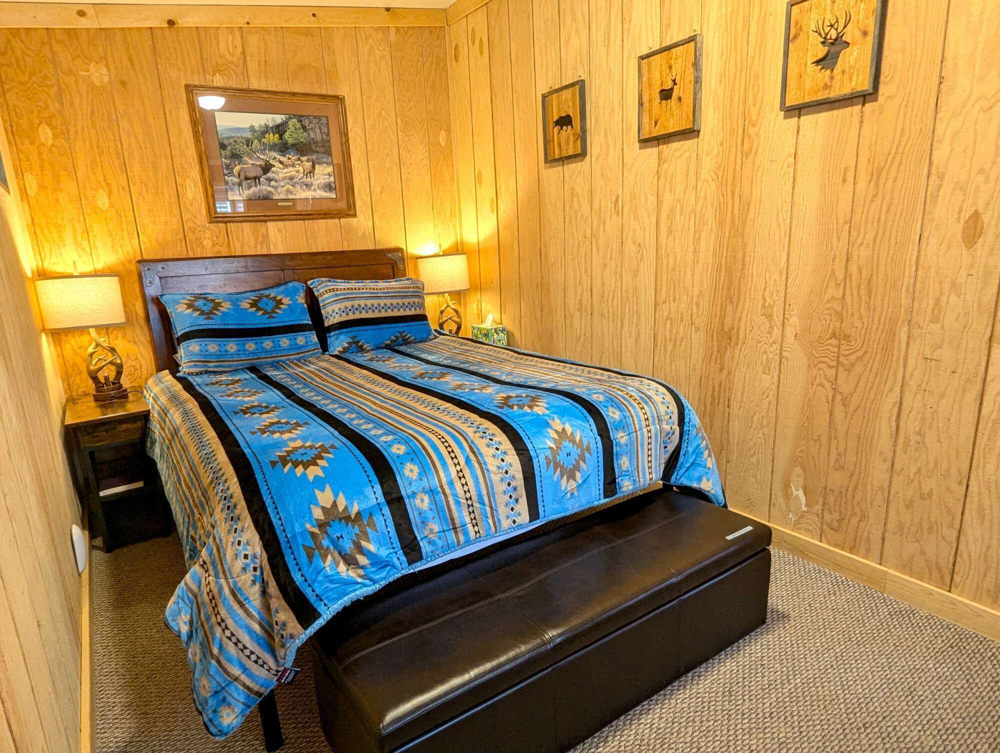 Una habitación con paneles de madera, una cama, dos lámparas de noche y siluetas de animales enmarcadas en la pared.