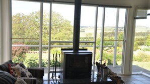 Una habitación con un ventanal grande, chimenea y vistas a un paisaje verde.