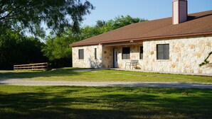 A stone building with a red roof, a front porch, and a gravel driveway. - Country-style Oasis! The perfect family get-away. VIEW OUR VIDEO!  (San Antonio)