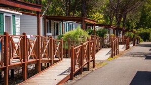 Rivi puisia mökkejä, joissa on vihreät ikkunaluukut, ja ne on yhdistetty puisilla kävelysilloilla.