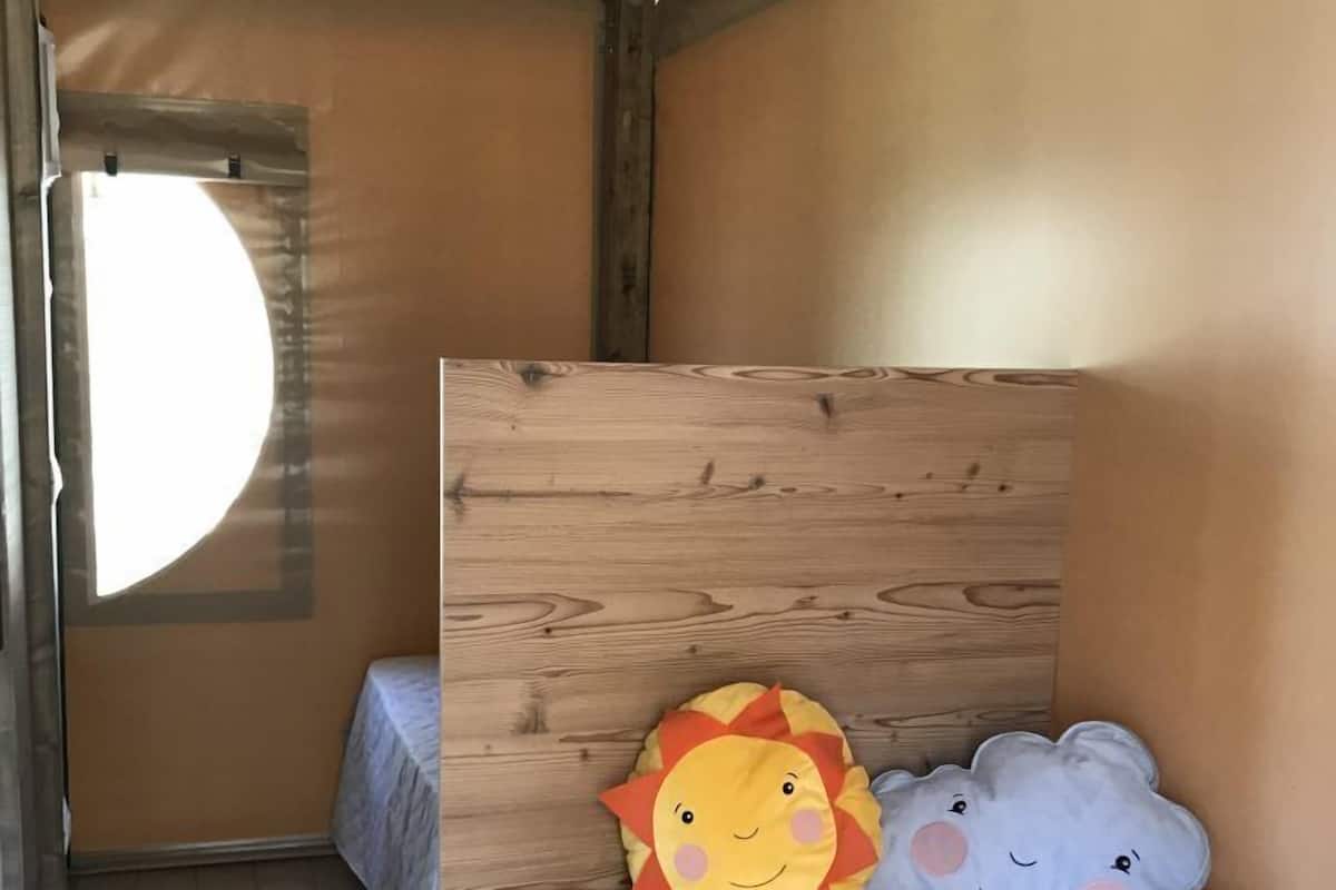 Ein kleines, gemütliches Zimmer mit einem Holzbett, einem runden Fenster und zwei bequemen Kissen.