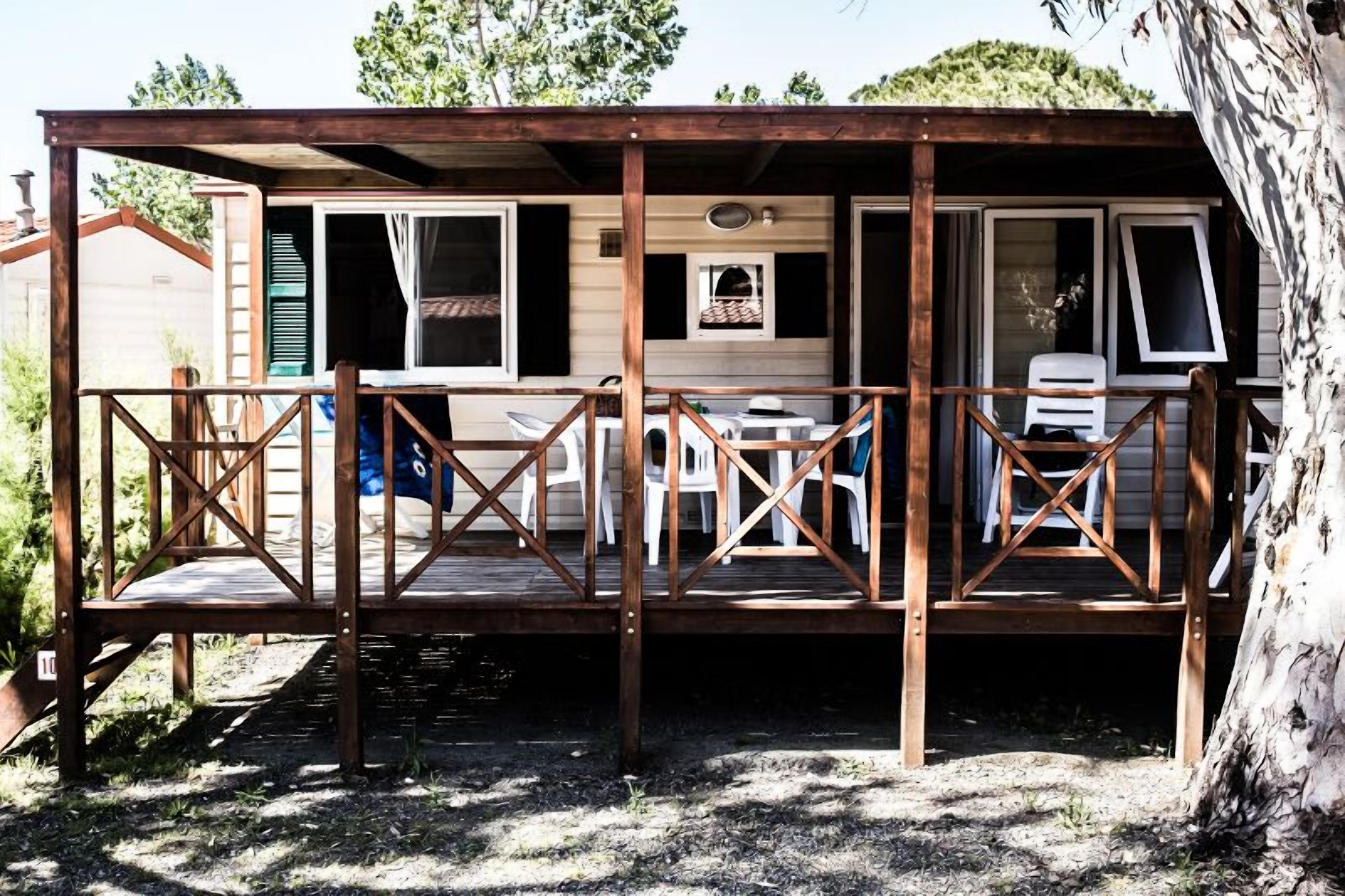 Een houten terras met een hekwerk, een tafel en stoelen.