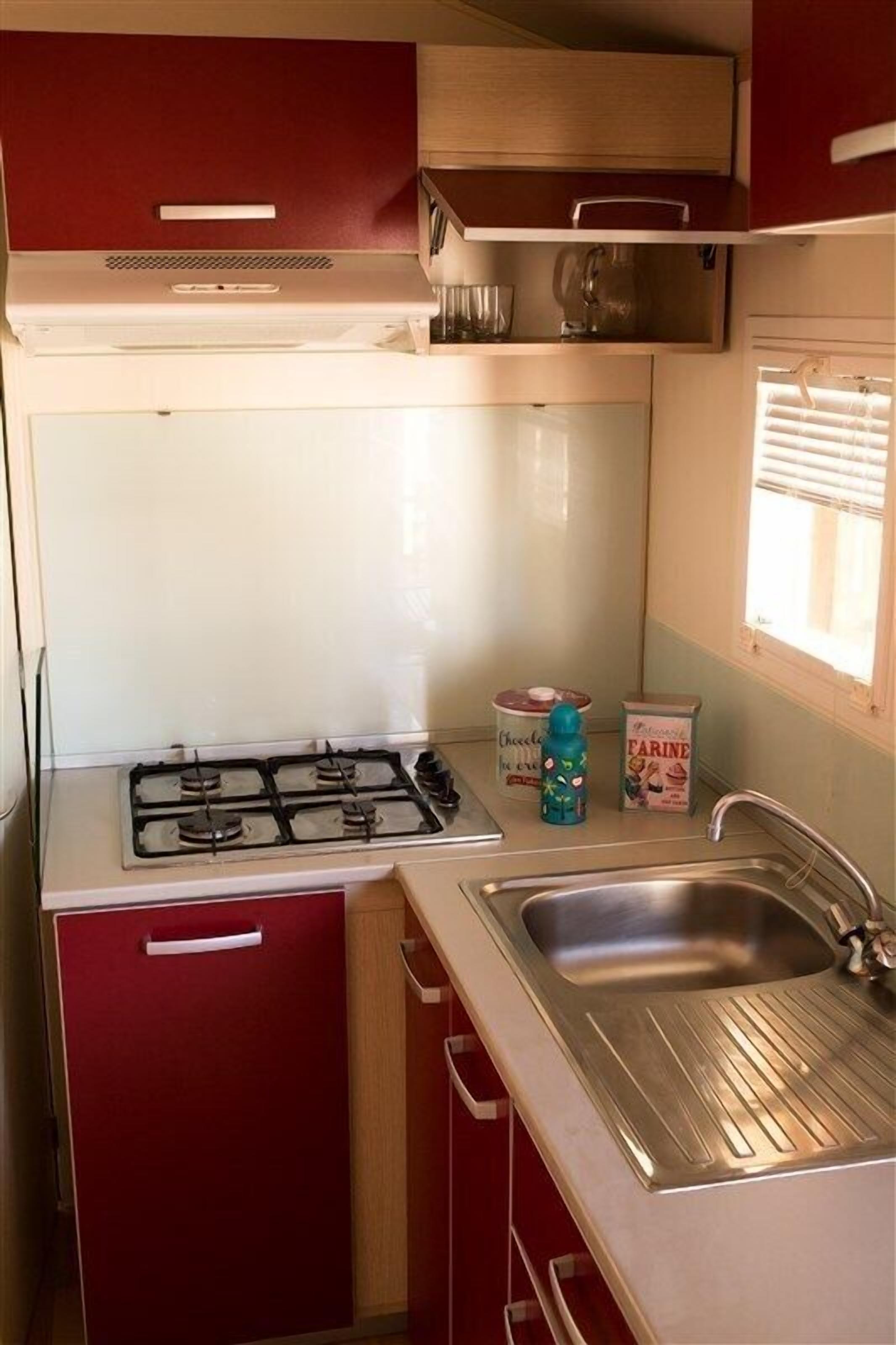 A compact kitchen with a gas stove, a sink, and cabinets.