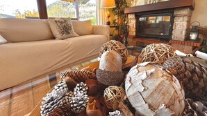Una sala de estar acogedora con un sofá, una chimenea y una mesa de centro de vidrio con adornos.