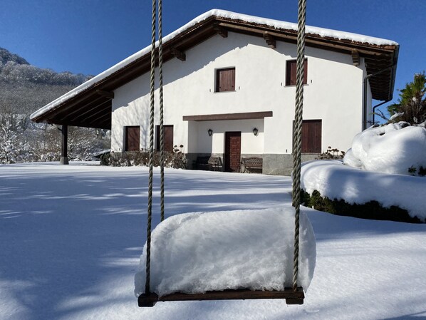 A snow-covered house with a swing in the foreground. - Self catering Etxaburu for 8 people (Larraun)