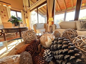 A cozy living room with wicker furniture, a glass coffee table, and a view of the outdoors through large windows. - Self catering Etxaburu for 8 people (Larraun)
