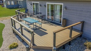 Une terrasse avec des meubles d’extérieur, un patio couvert et une maison dotée de grandes fenêtres et d’une porte.