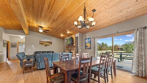 Un espace repas avec une table et des chaises en bois, un ventilateur de plafond et une vue sur l’extérieur.