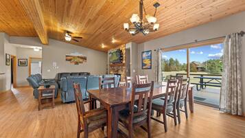 A dining area with a wooden table and chairs, a ceiling fan, and a view of the outdoors.