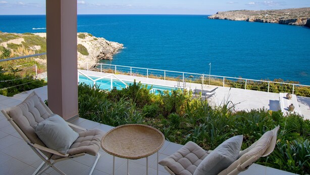 Un balcó amb piscina, gandules i vista al mar.