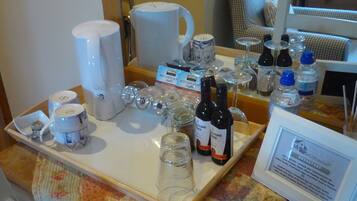 A breakfast tray with hot chocolate mugs, wine glasses, and bottles of wine.