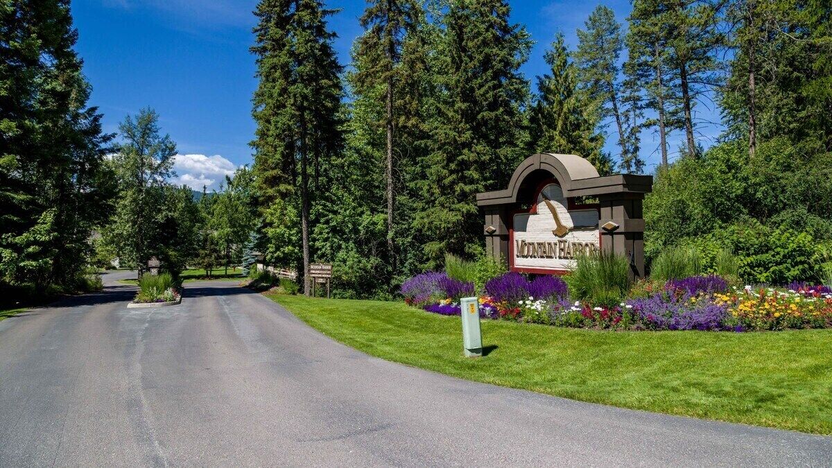 A sign for a hotel with a landscaped garden and a road leading to it.