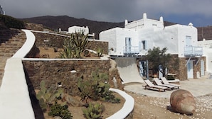 A white building with a stone wall and cactus garden. - 200μ από τη παραλία  (MYKONOS)