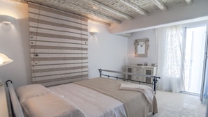 A bedroom with a bed, a dresser, a mirror, and a window with curtains. - 200μ από τη παραλία  (MYKONOS)