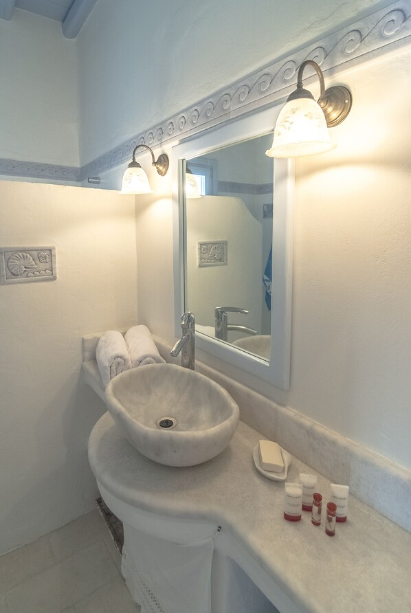 Un baño con un lavamanos blanco, un espejo y dos luces fijadas a la pared.