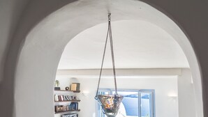 A cozy living room with a view through an arched doorway, featuring a bookshelf, a coffee table with decorative items, and a television on a wooden cabinet. - 200μ από τη παραλία  (MYKONOS)