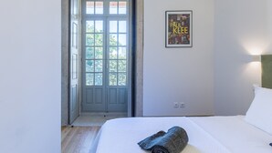 Een slaapkamer met een bed, een lijst aan de muur en een deur naar een buitenruimte.