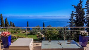 Ein Balkon mit Meerblick, eine Sitzecke mit Tisch und Stühlen sowie Kübelpflanzen.