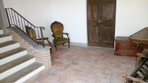 A staircase with a brick base and metal railing, a wooden chair, a wooden door, and a wheelbarrow. - From the Piero hill you can admire the Valtiberina where Tuscany and Umbria merge (Sansepolcro AR)