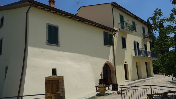 A two-story building with a light-colored facade, a wooden door, and a small window. - From the Piero hill you can admire the Valtiberina where Tuscany and Umbria merge (Sansepolcro AR)